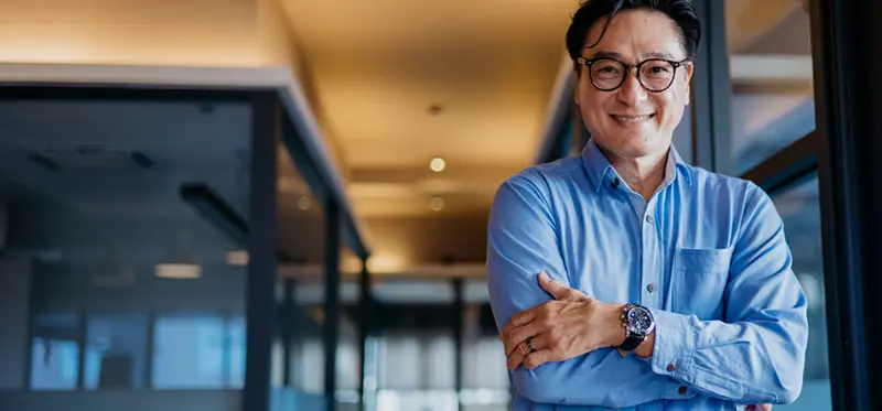 Male person with glasses smiling and arms crossed